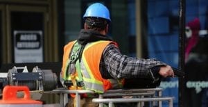 Image of construction worker onsite with hard hat performing safety reporting